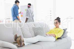 Young creative woman using laptop on couch