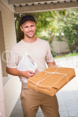 Delivery man smiling at camera offering parcel