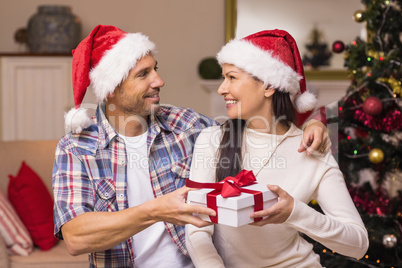 Happy couple in santa hat holding present