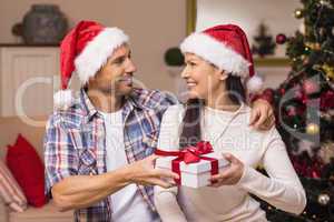 Happy couple in santa hat holding present
