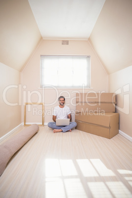 Happy man using laptop surrounded by boxes