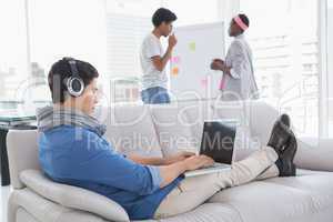 Young creative man using laptop on couch