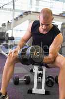 Young man exercising with dumbbell in gym