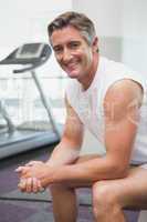 Fit man smiling at camera in fitness studio