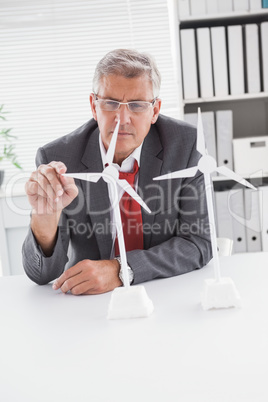 Businessman looking at model wind turbines