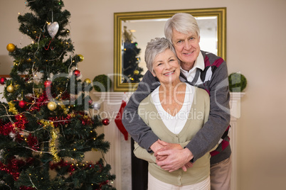 Senior couple hugging beside their christmas tree