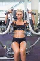 Fit young woman using fitness machine at gym