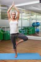 Sporty woman standing in tree pose at fitness studio