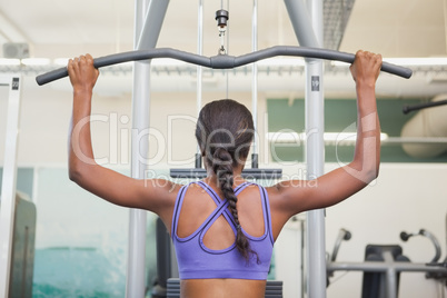 Fit woman using the weights machine for her arms