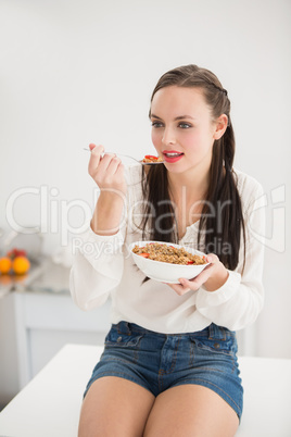 Pretty brunette eating bowl of cereal