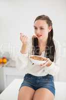 Pretty brunette eating bowl of cereal