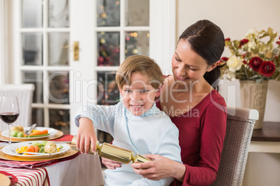 Little boy pulling a christmas cracker with his mother