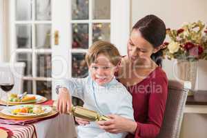 Little boy pulling a christmas cracker with his mother