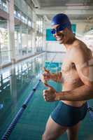 Swimmer gesturing thumbs up by pool at leisure center