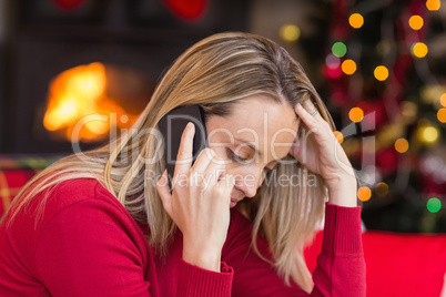 Upset young woman looking down while calling on phone