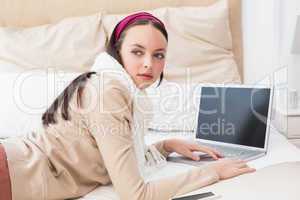 Pretty brunette using laptop on bed