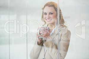 Businesswoman holding cup of coffee through the window