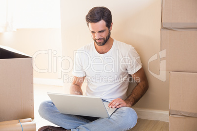 Happy man using laptop surrounded by boxes