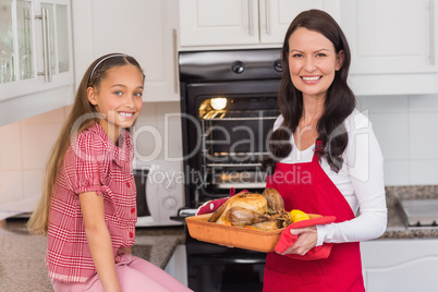 Happy mother and daughter posing with roast turkey