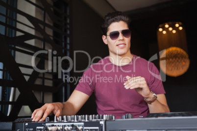Cool dj in sunglasses working on a sound mixing desk