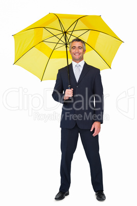 Smiling businessman under yellow umbrella