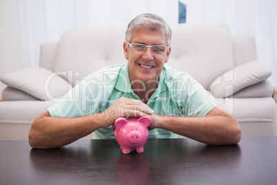 Smiling mature man with piggy bank