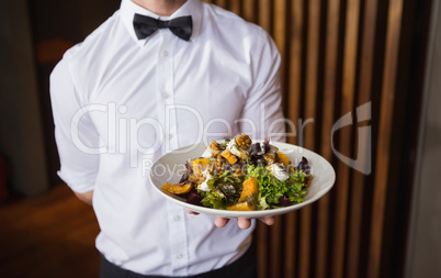Waiter showing plate of salad to camera
