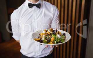 Waiter showing plate of salad to camera