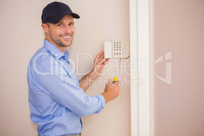 Smiling handyman fixing an alarm system