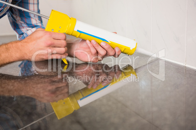 Plumber putting filling in between tiles