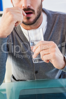 Mid section of a man with glass of water and pill