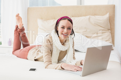 Pretty brunette using laptop on bed Pretty brunette using laptop on bed