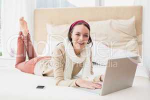 Pretty brunette using laptop on bed