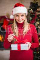 Smiling woman in santa hat opening a gift