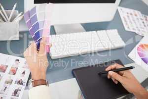 Designer working at desk using digitizer and colour sample