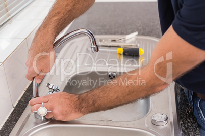 Man fixing tap with pliers