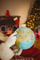 Santa pointing his finger on the globe