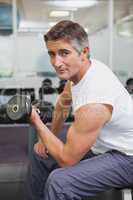Fit man lifting dumbbells sitting on the bench
