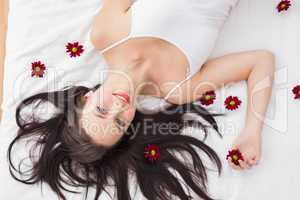 Pretty brunette posing in bed with flowers