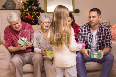 Cute little girl offering gift to her family