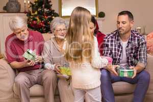 Cute little girl offering gift to her family