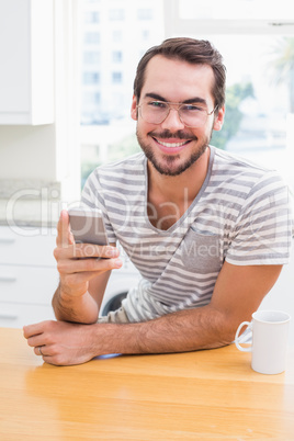 Young man using smartphone while having coffee