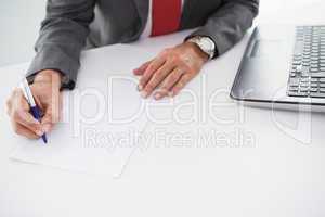 Mature businessman writing on document