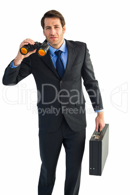 Serious businessman holding binoculars and a briefcase