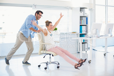 Smiling photo editors having fun with on a swivel chair