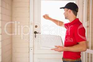 Delivery man holding pizza while knocking on the door