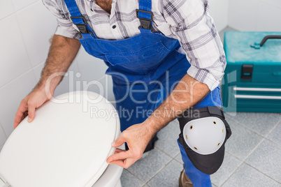 Plumber installing lid on toilet