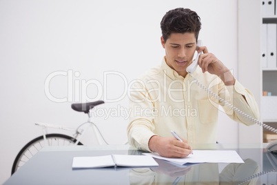 Cheerful businessman on the phone taking note