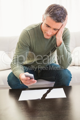 Smiling man using mobile phone near ripped paper