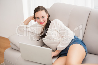 Pretty brunette using laptop on the couch